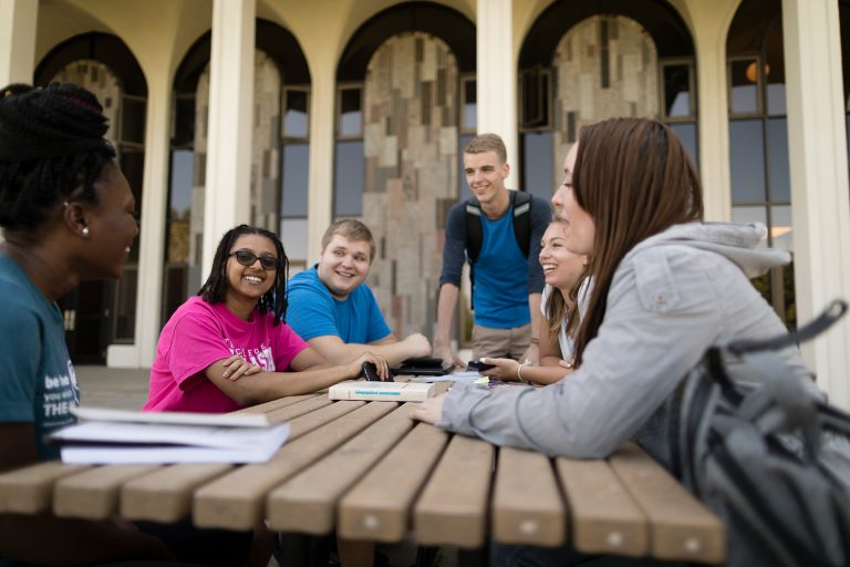 Students gather at a picnic table outside of the Science Center
