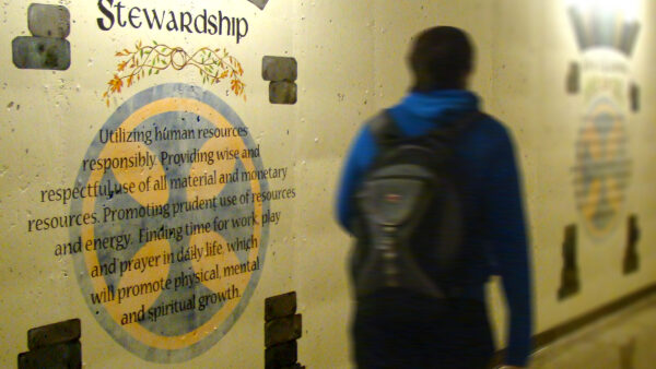 Student walks by a mural of the Benedictine value of stewardship.