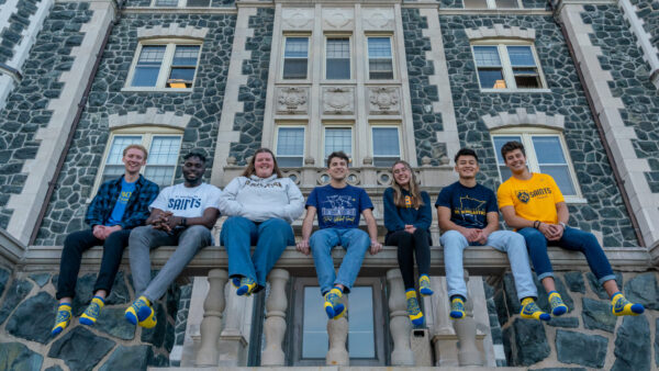 Seven students sitting on the ledge of Tower Hall for Give to CSS Day.