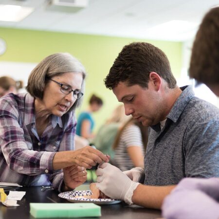 A St. Scholastica Professor teaching students to suture.