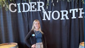 Olivia Niska poses beneath a Cider North banner at the Duluth DECC event.