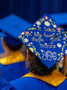 St. Scholastica graduate wearing a cap that says "It takes a big heart to shape little minds"