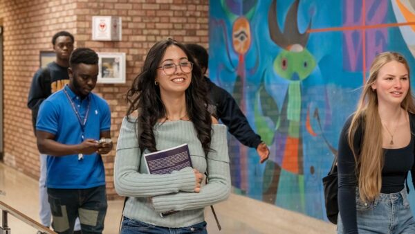 St. Scholastica student El Hamdani walking with students in front of a mural.