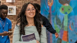 St. Scholastica student El Hamdani walking with students in front of a mural.