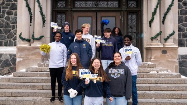 St. Scholastica students stand in front of Tower Hall with Give to CSS signs.