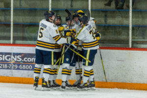 Members of the St. Scholastica Men's Hockey team gathered in celebration on the ice.