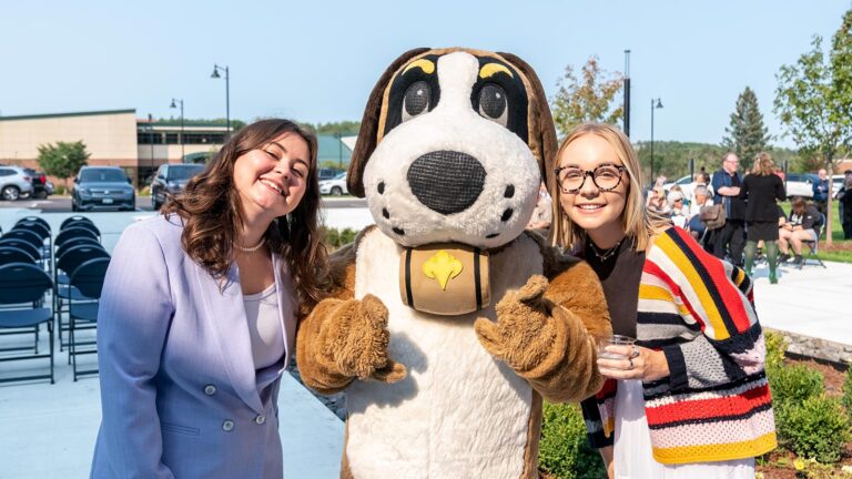 Two St. Scholastica graduates pose with storm at an alumni event.