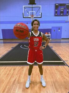 Photo of Briana Allen stands on a basketball court holding a basketball