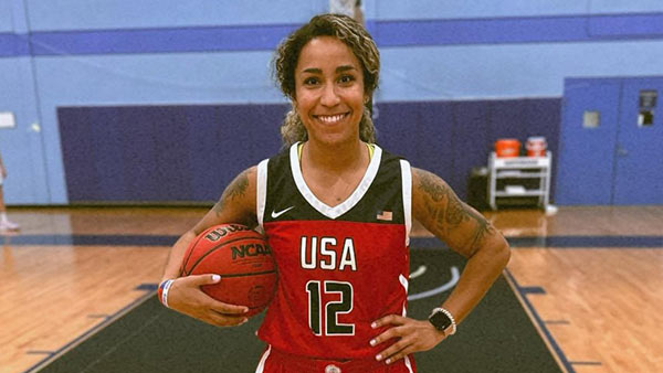 Photo of Briana Allen stands on a basketball court holding a basketball
