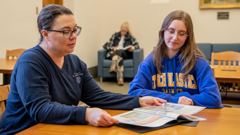 Photo of a St. Scholastica Staff member walking student through documents