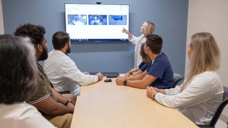 St. Scholastica nursing students and instructors in a debrief room discussing a simulation