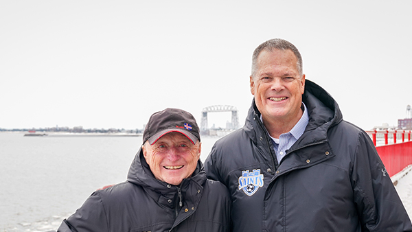 Kenny Harkins and Dan Seeler pose together in front of lake superior