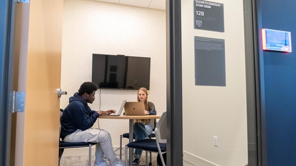 Two St. Scholastica students use a study room in the Student Center
