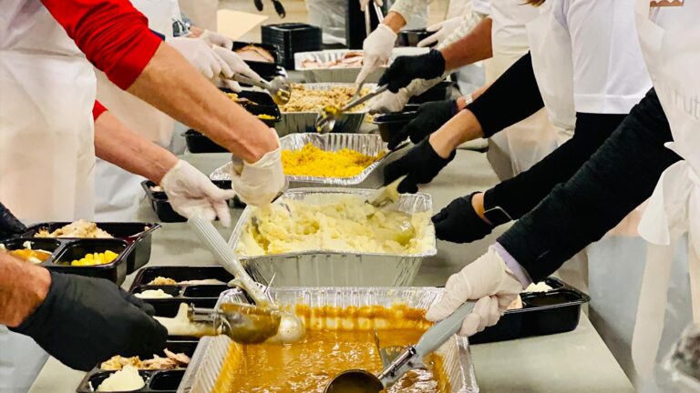 Photo of Volunteers dishing up food for St. Scholastica's Thanksgiving Day Buffet.