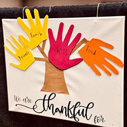Photo of a thanksgiving decoration made by a child. It's a tree made with handprints cut out of construction paper