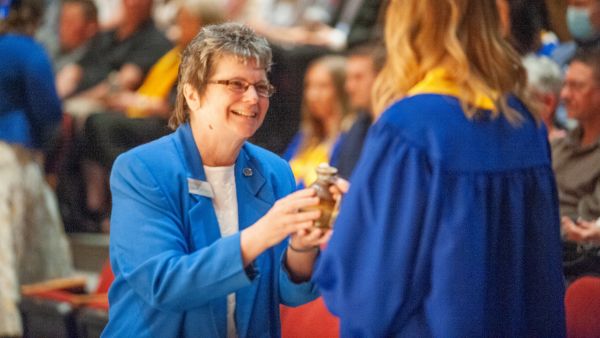 Sister Kathleen hands a student an oil lamp as part of Spring 2022 commencement.