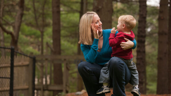 A mother holding and signing to her child.