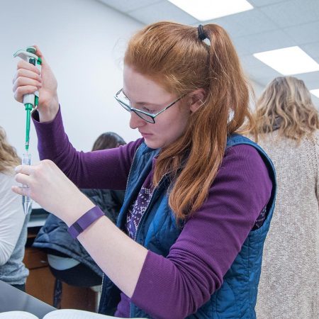 St. Scholastica student conducting an experiment in a science lab.