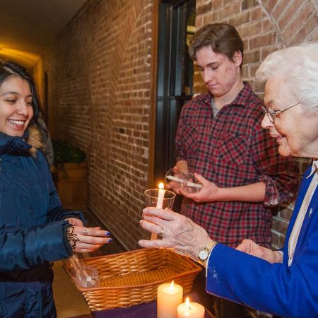 One of the Sisters handing a candle to a student.