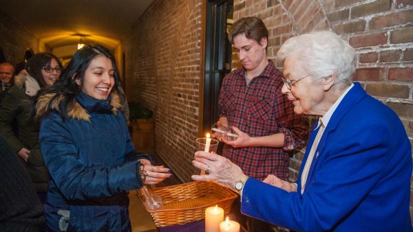 One of the Sisters handing a candle to a student.