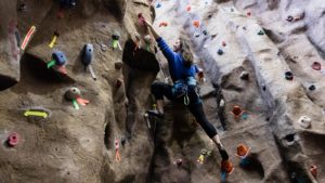 Female student scaling the indoor climbing wall.