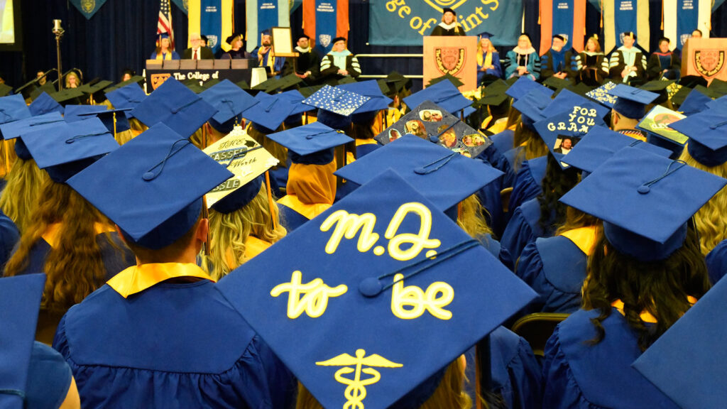St. Scholastica commencement ceremony. A view of graduates's caps. One says M.D. to be.