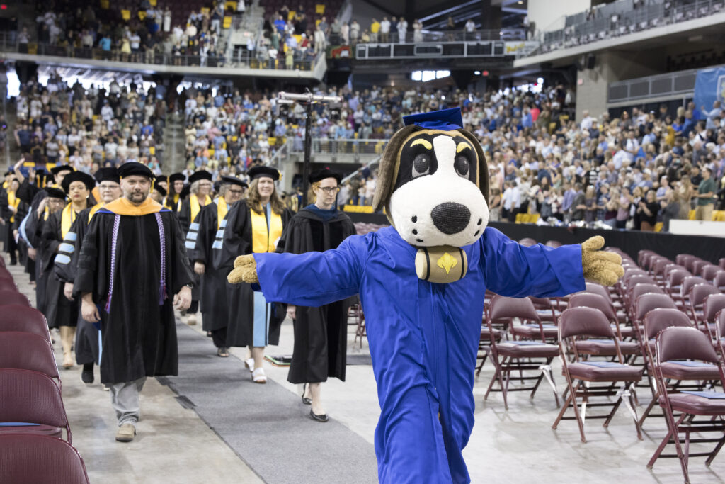 Storm, the St. Scholastica mascot, leads the procession for commencement.