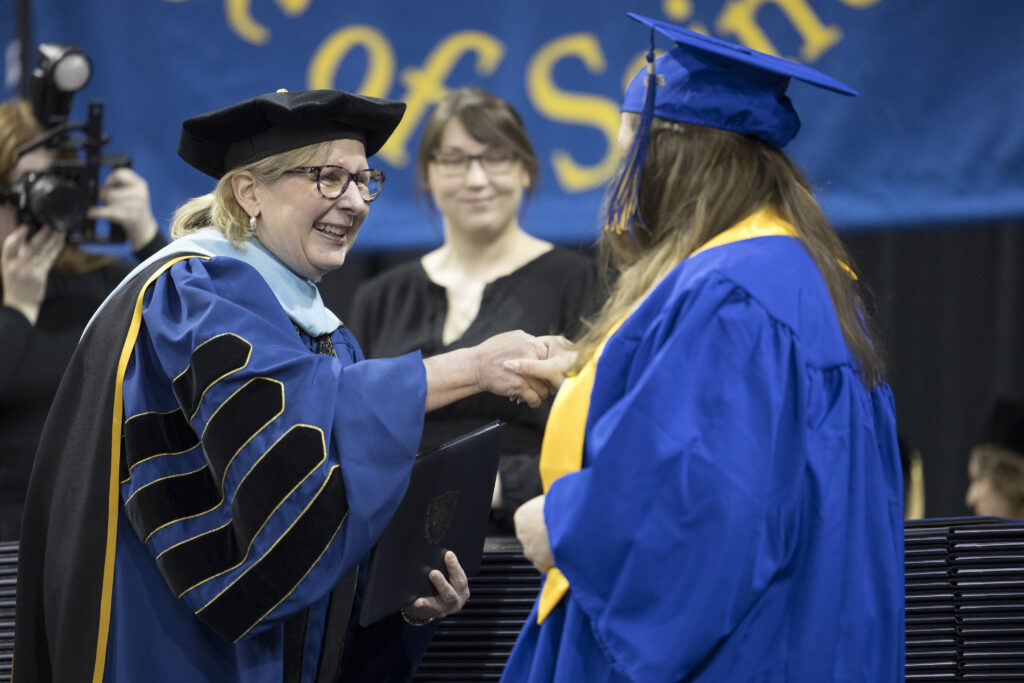President Barbara McDonald shakes the hand of a new graduate.