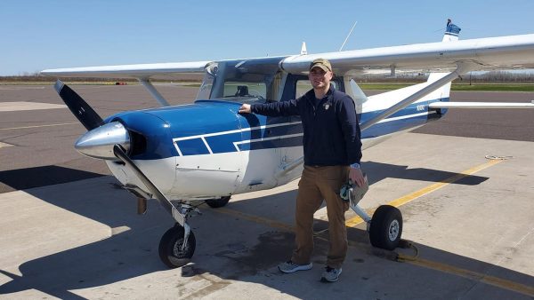 Eric DeLaVergne standing in front of a small plane at an airport.