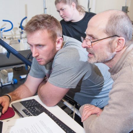 Professor working with exercise physiology students in a lab setting at St. Scholastica.