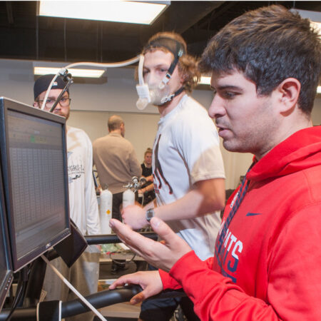A runner on a treadmill being monitored by exercise physiology equipment.