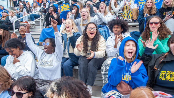 A group of students cheer on the St. Scholastica Saints during a football game.