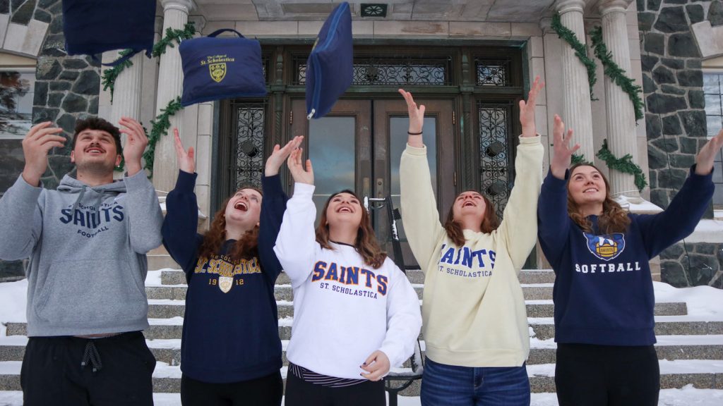 A group of students on the steps of Tower Hall tossing blankets into the air.