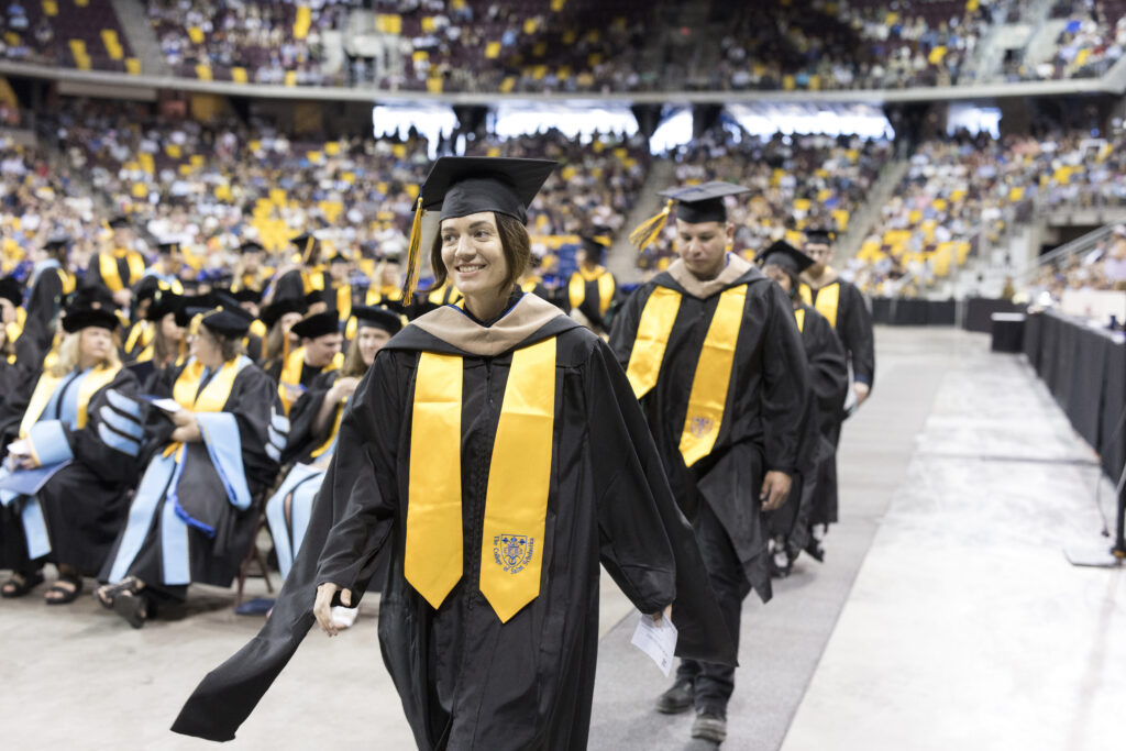 Graduate students walking up to the graduation stage.