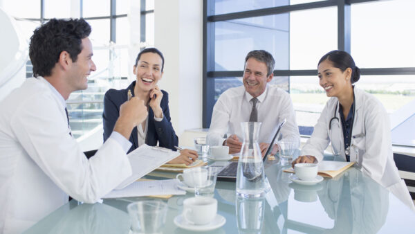 A group of healthcare professionals networking with business executives in a conference room setting.