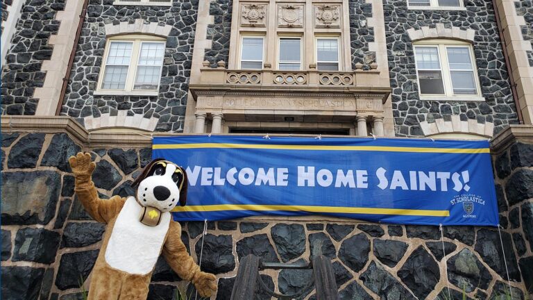 St. Scholastica mascot Storm in front of a welcome home banner.