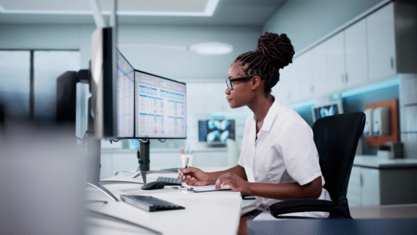 Hospital Doctor Using Spreadsheet For Billing Codes On Desktop.
