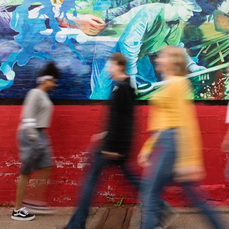 Students walking past a mural painted by Professor Paul LaJeunesse.