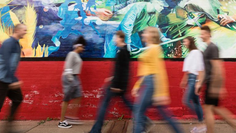 Students walking past a mural painted by Professor Paul LaJeunesse.