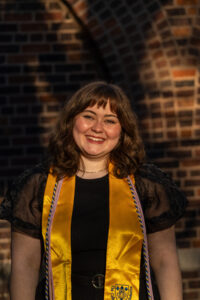 Maddy Ploof in graduation garb in front of Tower Hall.