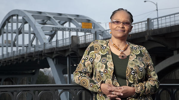 Ms. Lowery standing in front of a bridge. Photo by Robin Cooper of Penguin Random House.