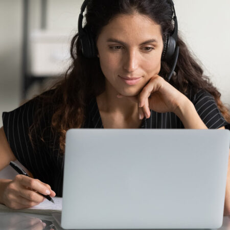 College student listening to an online course lecture on her laptop.
