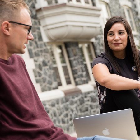 Two St. Scholastica students sitting on the steps of Tower Hall.