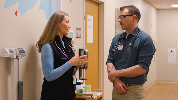 A St. Scholastica PA Medicine student talking with a healthcare provider in the hallway of a rural medical facility.
