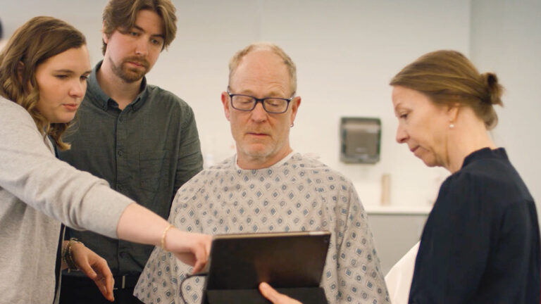 Two St. Scholastica PA Medicine students working with a professor to explain ultrasound results to a patient.