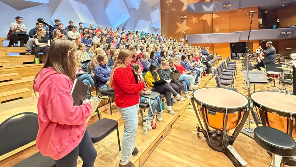 St. Scholastica's choral group on stage with other performers in Orchestra Hall.