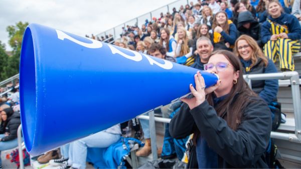 Student and crowd cheering at Homecoming.