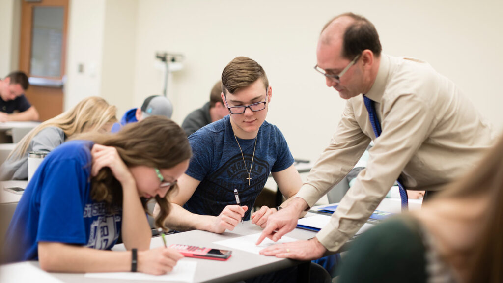 St. Scholastica professor assisting two students with an assignment during class.