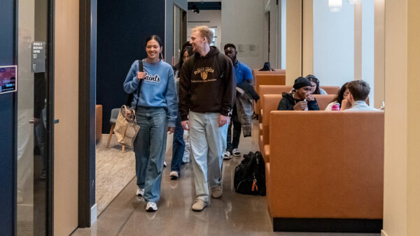 St. Scholastica students studying in booths in the Student Center as a group of students wearing Saints gear walk by in the aisle.
