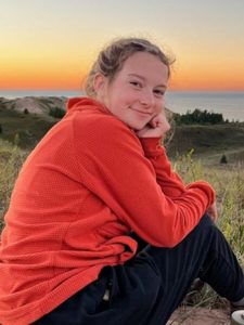 Tatum Severson sitting on a hill near Lake Superior.
